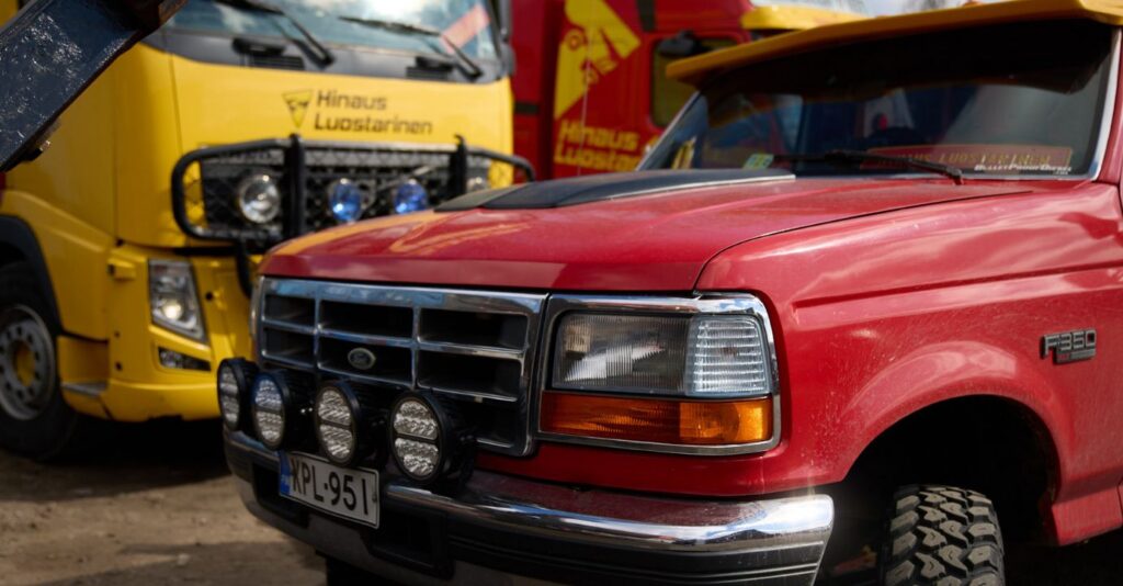 Garage-mallinen punainen ford-merkkinen hinausauto ja takana keltainen volvo hinausauto
