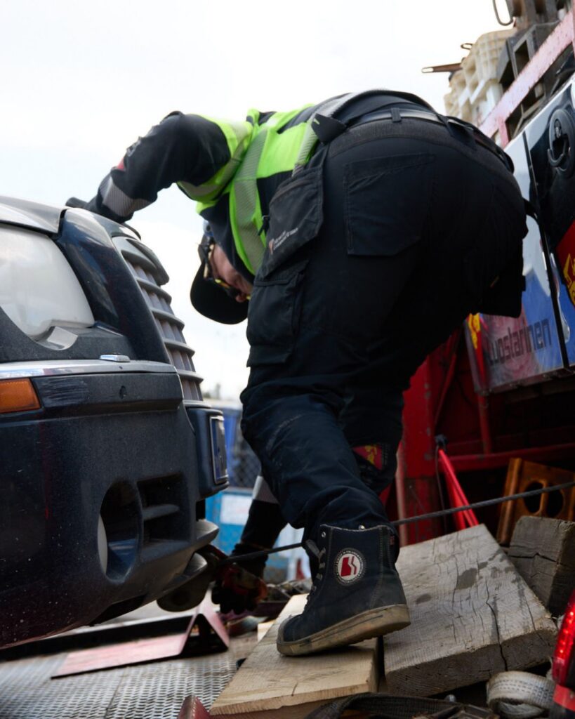 hinausauton kuljettaja sitomassa hinattavaa autoa